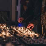 Aansteken van kaarsjes tijdens Lichtjesavond 2025 Zichtbaar zijn een verzameling waxinelichtjes en 2 handen met een aansteker die de handeling van het aansteken uitvoeren.